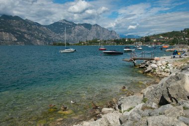MALCESINE, İtalya - 30 AĞUSTOS 2023: Arka planda dağlar olan Garda Gölü 'nün güzel manzarası, Veneto, İtalya