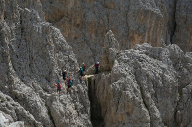 TORRI DEL VAJOlet, İtalya - 3 Eylül 2023: dağdaki klinikler. Dağlarda tehlikeli yollarda olan turistler. Yürüyüş yolu zor. İtalyan Dolomitlerinde zincirli taş. Aşırı seyahat ve adrenalin