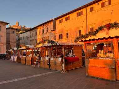 ASSISI, İtalya - 18 ARALIK 2023: Günbatımında Umbria, İtalya 'daki Assisi' li Aziz Chiara meydanındaki geleneksel noel pazarına