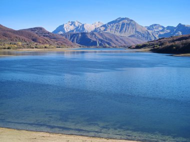 Campotosto Gölü 'nün sonbahar mevsiminde arka planda yüksek dağ, Abruzzo Bölgesi, İtalya