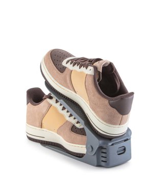 Ayarlanabilir düzenleyici, bej ve kahverengi spor ayakkabılı bir çift ayakkabıyı saklamak ve göstermek için tasarlanmış, beyaz üzerinde izole edilmiş. Ayakkabı şeklini korumak ve yer ayırmak için kullanışlı bir aksesuar