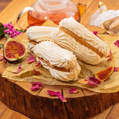 Yumuşak, çıtır çıtır, incir kremalı sandviçler çay ortamının ortasındaki ahşap tahtada sunuluyor. Tatlı ikramlarla çay içmenin keyifli anı