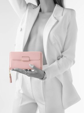 Beyaz takım elbiseli, düğmesiz ceketli zarif pembe deri debriyajlı, altın sarısı ve püsküllü bir kadın resmi. Kısmi doygunluk etkisi olan biçimlendirilmiş fotoğraf