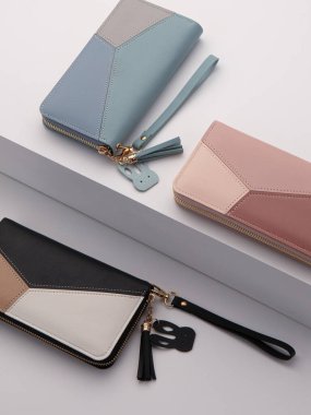 Pastel pembe ve çıplak renkte zarif kadın debriyajı geometrik desenli, altın fermuar, güvenli bileklik kayışı ve beyaz ayakta sunulan dekoratif püsküller.