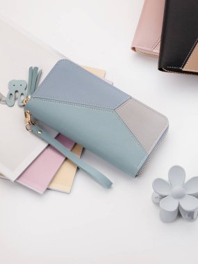 Pastel pembe ve çıplak renkte zarif kadın debriyajı geometrik desenli, altın fermuar, güvenli bileklik kayışı ve beyaz ayakta sunulan dekoratif püsküller.