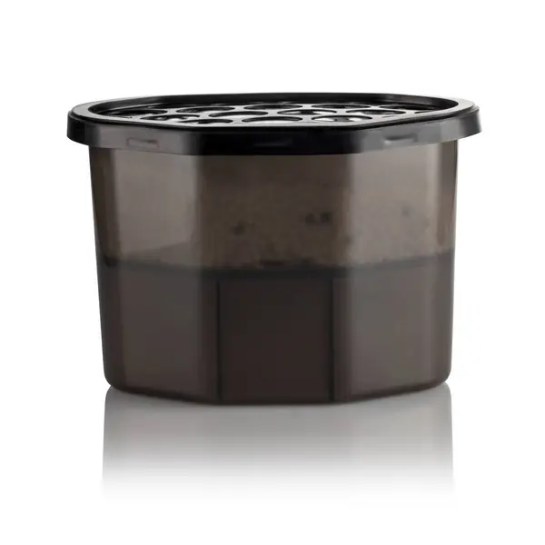 stock image Moisture absorber half filled with hygroscopic granules visible through semi-transparent brown container, with vented black lid on top and clean label area for branding or product informatio