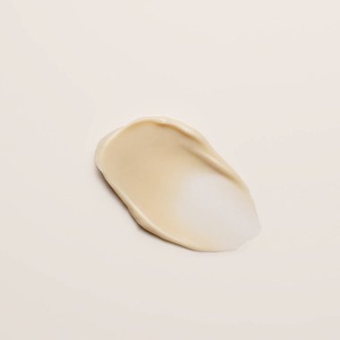 Beyaz arkaplana sürülmüş tek canlı sarı krem kozmetik ürünü, renk karşılaştırması ve doku analizi için idealdir.