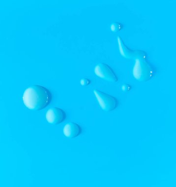 Parlak mavi arkaplana serinletici damlacıklar ve nemlendirici berrak cilt jeli, kozmetik ürünün berraklığını ve saflığını vurguluyor. Soyut minimalist kompozisyon