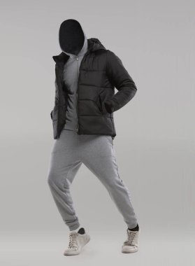 Tarz sahibi bir siyah ceket, arka planı sade bir stüdyoda duran yüzü olmayan bir modelin üzerinde gri eşofmanla eşleştirilir. Giyim kuşamında gündelik kıyafetlerin modern moda eğilimleri sergileniyor.