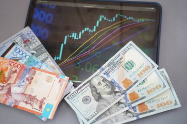 Almaty, Kazakistan - 10.04.2022: Tablet üzerindeki borsa tableti, tenge ve masadaki dolar banknotları.