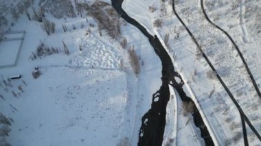 Şehrin orta kesimindeki donmuş bir göl ve nehrin üzerinde, yerleşim yerlerinin arasında uçuyor..
