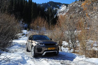 Almaty, Kazakistan - 02.29.2016: Bir Range Rover Evoque aracının kış mevsiminde dağlık bir alanda test sürüşü.