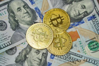 Almaty, Kazakistan - 04.04.2023: Bitcoin paraları 100 dolarlık banknotların üzerine istiflenmiş.