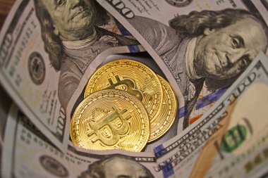 Almaty, Kazakistan - 04.04.2023: Bitcoin paraları 100 dolarlık banknotların üzerine istiflenmiş.