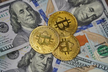 Almaty, Kazakistan - 04.04.2023: Bitcoin paraları 100 dolarlık banknotların üzerine istiflenmiş.