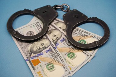 Almaty, Kazakistan - 04.06.2023: Kelepçeler masadaki yüz dolarlık banknotların üzerinde..