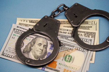 Almaty, Kazakistan - 04.06.2023: Kelepçeler masadaki yüz dolarlık banknotların üzerinde..