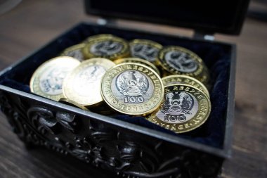 Almaty, Kazakistan - 04.05.2023: 100 Kazakistan tentesi yüzölçümü olan bir avuç dolusu bozuk para bir tabutta katlandı.