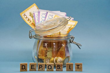 Almaty, Kazakistan - 04.05.2023: Bozuk paralar ve onluk banknotlarla dolu bir banka yazıtların arkasında duruyor.