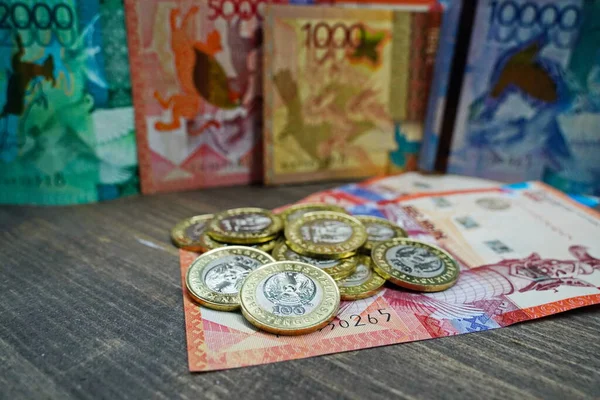 哈萨克斯坦阿拉木图 2023 一大把面值为100哈萨克斯坦坚戈的硬币堆放在钞票上 — 图库照片