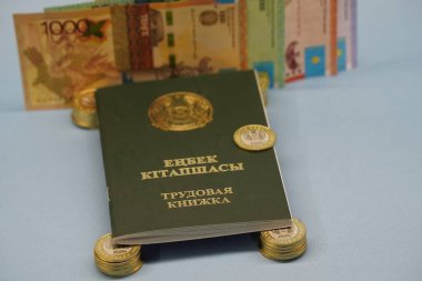 Almaty, Kazakistan - 04.05.2023: Kazakistan Cumhuriyeti 'nin istihdam kaydı banknotların arka planındaki tenge paralarının üzerinde duruyor