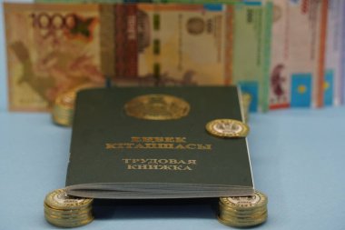 Almaty, Kazakistan - 04.05.2023: Kazakistan Cumhuriyeti 'nin istihdam kaydı banknotların arka planındaki tenge paralarının üzerinde duruyor