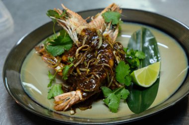 Soğan soslu karides ve tabakta limon..