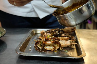 Aşçı karides tabağına soğan sosu döker.