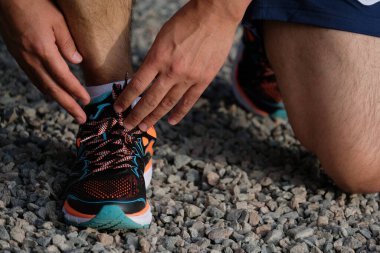 Almaty, Kazakistan - 06.19.2018: Koşmadan önce ayakkabı bağcıklarını spor ayakkabılarına bağlayan bir adam.
