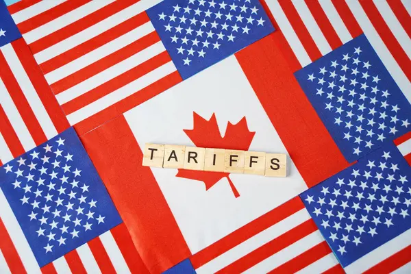 Yazı: Kanada bayrağının arka planındaki tarifeler ve ABD bayrakları..