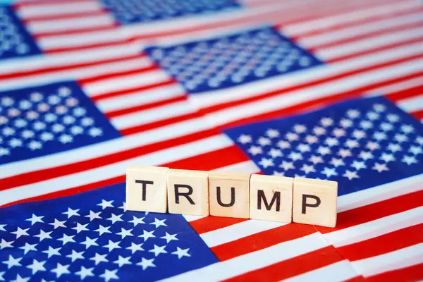 ABD bayraklarının arkaplanındaki Trump yazısı.
