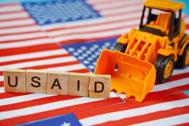 ABD bayrağının arka planında USAID yazıları ve buldozer.