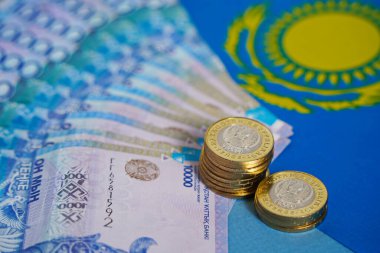 Masanın üzerine, Kazakistan bayrağının arka planına karşı onluk banknotlar ve sikkeler serilmiştir..