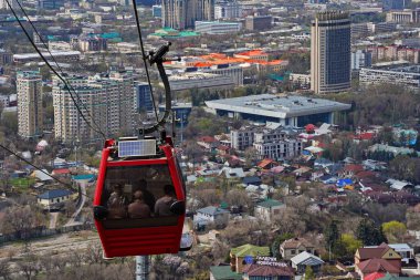 Almaty, Kazakistan - 04.07.2025: Turistlerle dolu bir kulübe şehrin üzerinde teleferiğe biniyor.