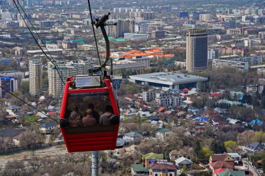 Almaty, Kazakistan - 04.07.2025: Turistlerle dolu bir kulübe şehrin üzerinde teleferiğe biniyor.