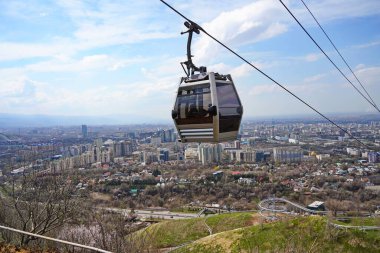Almaty, Kazakistan - 04.07.2025: Turistlerle dolu bir kulübe şehrin üzerinde teleferiğe biniyor.