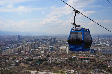 Almaty, Kazakistan - 04.07.2025: Turistlerle dolu bir kulübe şehrin üzerinde teleferiğe biniyor.