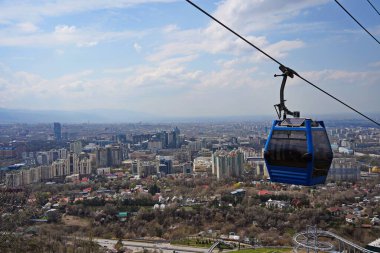 Almaty, Kazakistan - 04.07.2025: Turistlerle dolu bir kulübe şehrin üzerinde teleferiğe biniyor.
