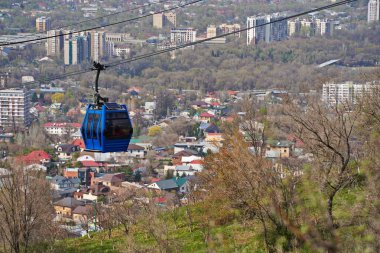 Almaty, Kazakistan - 04.07.2025: Turistlerle dolu bir kulübe şehrin üzerinde teleferiğe biniyor.