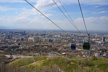 Almaty, Kazakistan - 04.07.2025: Turistlerle dolu bir kulübe şehrin üzerinde teleferiğe biniyor.