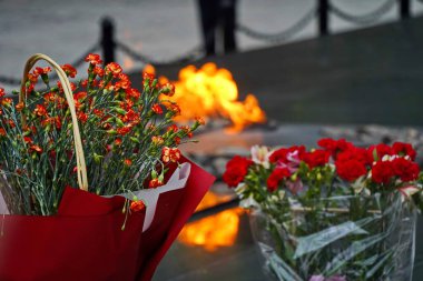 Sonsuz ateşin arka planında çiçekler. Anma Günü, 9 Mayıs.