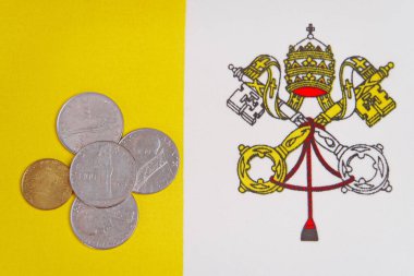 Vatikan bayrağının arka planında madeni paralar.