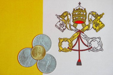 Vatikan bayrağının arka planında madeni paralar.