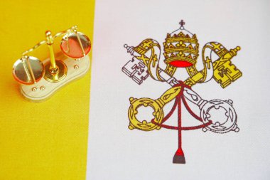 Vatikan bayrağının arka planında mini pullar var..