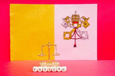 Vatikan bayrağının arka planında küçük pullar ve Vatikan yazıtları var..