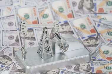Amerikan doları banknotlarının arka planında bir petrol platformu.