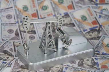 Amerikan doları banknotlarının arka planında bir petrol platformu.