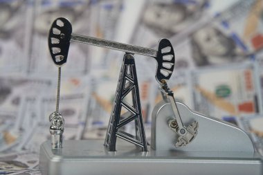 Amerikan doları banknotlarının arka planında bir petrol platformu.