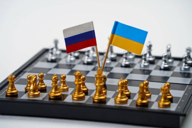 Rusya ve Ukrayna 'nın parçalarının ve bayraklarının olduğu bir satranç tahtası. Strateji, politik oyun ve diplomasi.