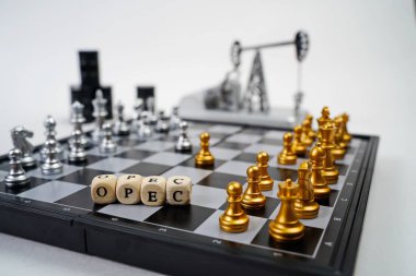 OPEC kelimesi. Parçalı bir satranç tahtası, yağ varilleri ve arka planda bir yağ pompası krikosu.